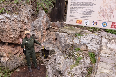 Ranger Lauren demonstrating wind flowing into the cavern.  This is the original hole into the cavern, and the earliest explorers crawled through it.<br>April 27, 2017