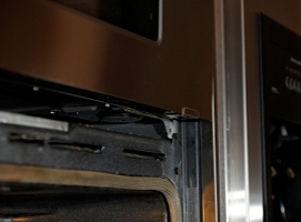 With the lower trim panel off, you can access two screws that hold the microwave in a sliding chassis.  The right screw has been removed here.