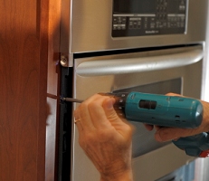 Removing one of the left side screws holding the microwave/oven assembly in place.