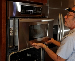 With the upper trim plate carefully removed, the microwave itself is finally free to slide forward, exposing the top.