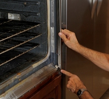 Now the steel side strips need to go back on.  Ron points to a small tab that needs to go inside (not visible) the strip.  When he took it off, he found that the previous tech had installed the strip incorrectly, with that little tab exposed.